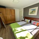 Schlafzimmer mit Doppelbett, Holzmöbel und Wandbild.