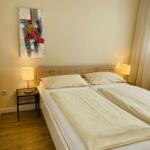 Schlafzimmer mit Doppelbett, Nachttischen und Wandbild.