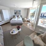 Ein Schlafzimmer mit Bett, Sofa, Tisch und Balkon. 