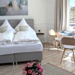 Schlafzimmer mit Doppelbett, Esstisch und Fensterblick auf Bäume