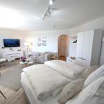 Schlafzimmer mit Doppelbett, Sofa, Fernseher und Kleiderschrank.