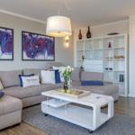 Wohnzimmer mit Sofa, Couchtisch und Wandregal. Auf der Wand hängen zwei Bilder.