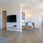 Wohn- und Essbereich mit TV, Tisch und Stühlen. Holzboden und moderne Einrichtung.