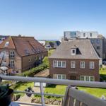 Blick von Balkon auf Straße, Häuser und Meer. Orchidee im Vordergrund.