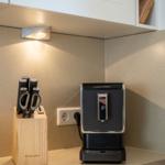 Küchenzeile mit Messerblock und Kaffeemaschine unter Schrank.