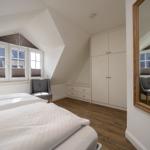 Schlafzimmer mit Dachschrägen, Bett, Kleiderschrank und Spiegel