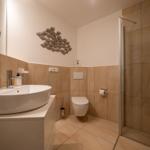 Badezimmer mit Dusche, Toilette und Waschbecken mit Wanddekoration.