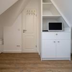 Schlafzimmer mit Dachschrägen, weißer Tür und TV-Schrank mit Schublade und Türen.