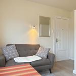 Gray sofa with cushions and blanket. Background: wall mirror and door.