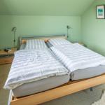 Schlafzimmer mit Doppelbett, grünen Wänden und Nachttischen mit Lampen.