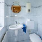 Badezimmer mit Waschbecken, Spiegel und Toilette. Wandfliesen mit Muster.