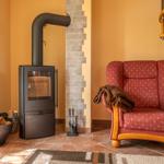 Kaminofen mit Holzstapel, rote Sessel und Holztreppe in Wohnzimmer
