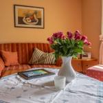 Ein Wohnzimmer mit Sofa, Tisch, Blumen und Fenster.