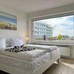Schlafzimmer mit Bett, Fenster und Blick auf Gebäude.
