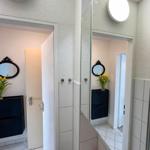 Badezimmer mit Spiegel, Waschbecken und dunklem Schrank. Gelbe Blumen auf dem Schrank.