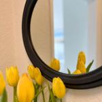 Runder Spiegel mit gelben Tulpen im Vordergrund