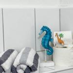 Badezimmer mit Handtuch, Seepferdchen-Dekoration und Toilettenpapierrolle.