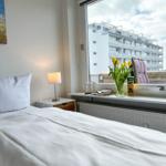 Schlafzimmer mit Bett, Nachttisch und Fensterblick auf Gebäude