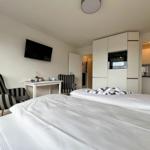 Schlafzimmer mit Bett, TV und Küchenbereich.