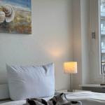 Schlafzimmer mit Bett, Wandbild und Lampe. Fenster zeigt Gebäude.
