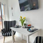 Esstisch mit zwei Stühlen, Fernseher und Blumen auf dem Tisch.