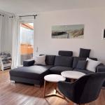Ein Wohnzimmer mit grauem Sofa, zwei runden Tischen und einem Bild an der Wand.