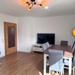 Essbereich mit Tisch, Stühlen und Fernseher. Holzboden und moderne Beleuchtung.
