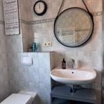 Badezimmer mit Waschbecken, Spiegel, Toilette und Dusche.