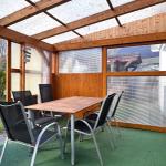 Terrasse mit Tisch und Stühlen unter Holzkonstruktion mit transparentem Dach.