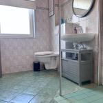 Badezimmer mit Toilette, Waschbecken und Dusche. Fliesenboden und Wandfliesen.