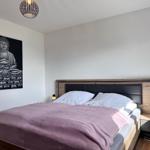 Schlafzimmer mit Bett, Nachttisch und Buddha-Bild an der Wand.