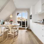 Kitchen and dining area with table, chairs, and balcony view.