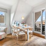 Dining room with table, chairs, and balcony access. Wooden floor and large window.