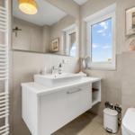 Bathroom with sink, mirror, window, and shower.