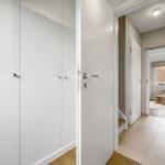 Hallway with white closets and door to living room with sofa.