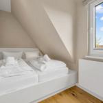 Room with two beds under sloped ceiling and large window with view of roof