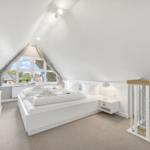 Bedroom with skylight, white bed, and TV cabinet.