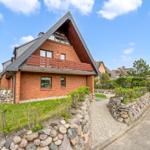 Red brick house with balcony and stone wall in the garden.