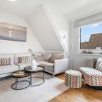 Living room with sofa, armchair, and table under sloped ceiling