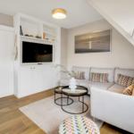 Living room with sofa, TV, and coffee table under sloped ceiling.