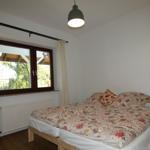 Schlafzimmer mit Doppelbett, Fenster und Deckenleuchte.