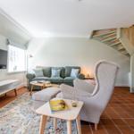 Living room with sofa, armchair, TV, and staircase.