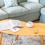 Living room with wooden table, cushions, and rug.
