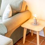 A sofa with cushions and a small table with a lamp.
