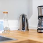 Kitchen counter with coffee maker, kettle, and water glass