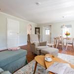 Living and dining area with seating, table and chairs. Wooden staircase and terracotta floor.