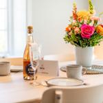 Table with flowers, bottle, and glasses for two people.