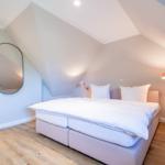 Bedroom with sloped ceiling, bed, wall mirror, and nightstand.