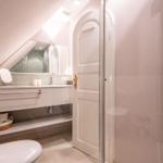 Bathroom with shower, sink, and toilet under sloped ceiling.