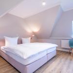 Bedroom with sloped ceiling, bed, chair, and window.
